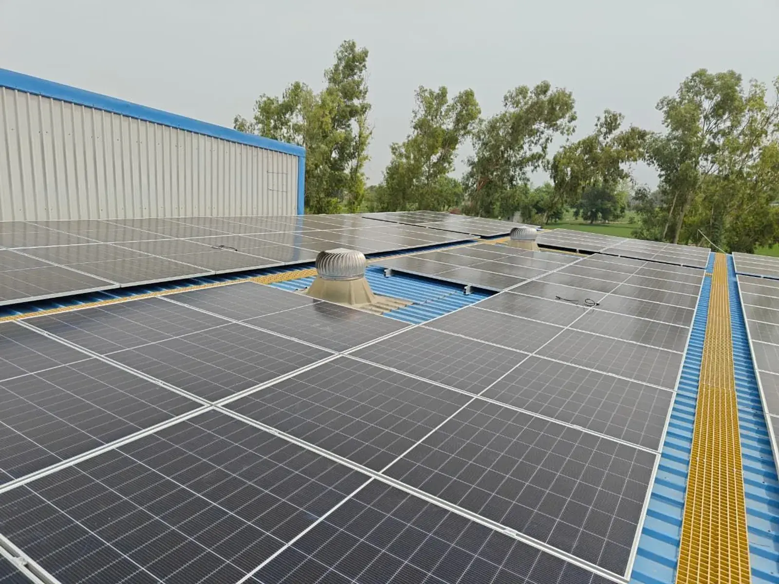 Completed rooftop solar array with a turbo ventilator and walkway at the rice shelling facility