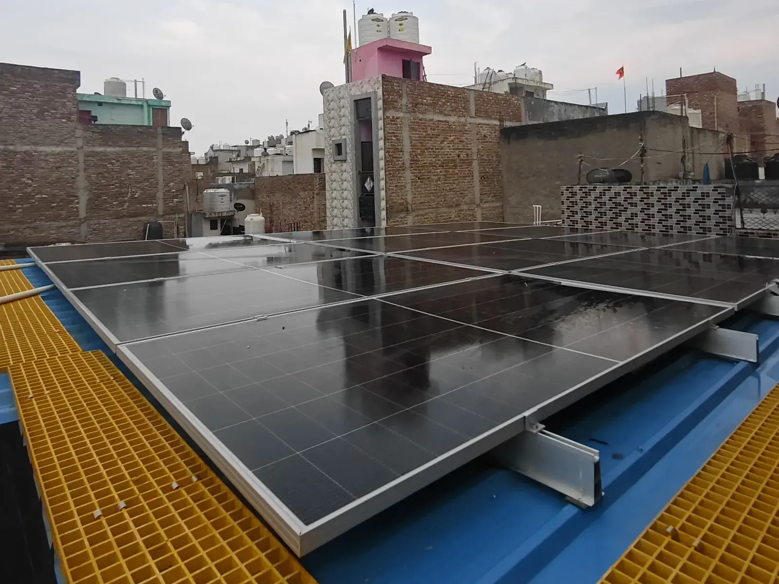 Completed solar array beside a yellow FRP walkway on the tin-shed roof